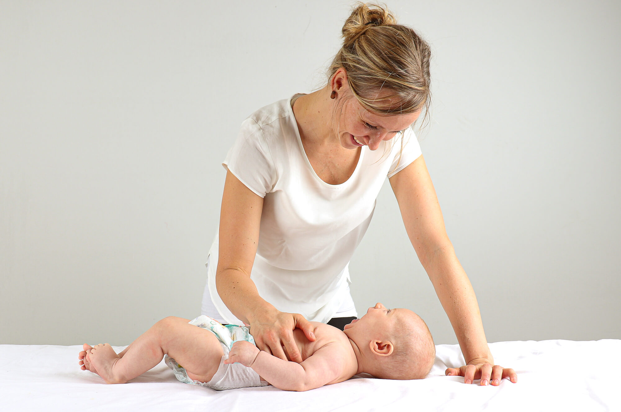 Osteopathin im Gespräch mit einer Mutter während der Behandlung ihres Babys